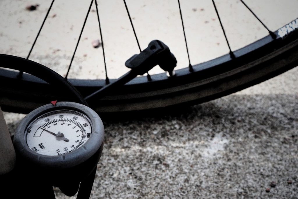 Picture of a bike tyre being pumped with a tyre pressure gauge.